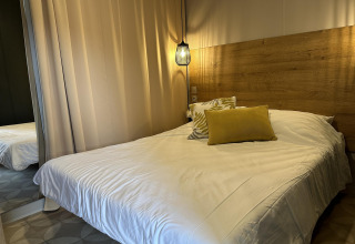 Dormitorio moderno en Mobilhome Toulouse, La Draille, Francia, con cabecero de madera y luz colgante cálida.