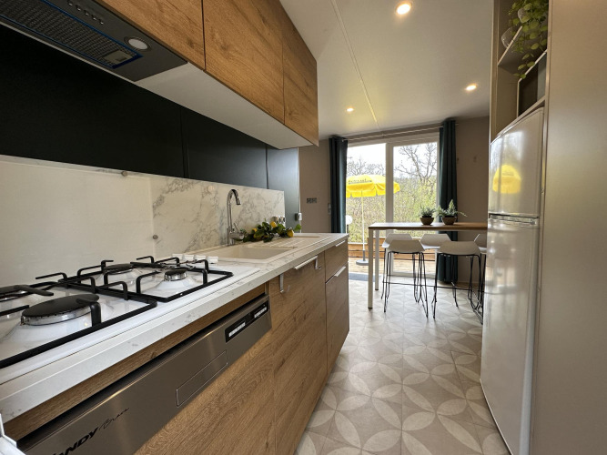 Cocina moderna en Mobilhome Toulouse en La Draille, Francia, con mesa de comedor y vista a la terraza.