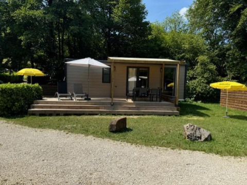 Mobilhome Toulouse à La Draille, France, avec terrasse, chaises longues et parasols jaunes dans un cadre vert.