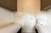 Chambre avec deux lits simples, literie blanche et une peluche dans Module II à Landgoed de Scheleberg, Pays-Bas.
