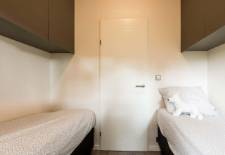 Slaapkamer met twee eenpersoonsbedden, wit beddengoed en een knuffelbeer in Module II op Landgoed de Scheleberg, Nederland.