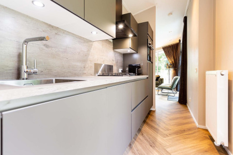 Cocina moderna de lodge con gabinetes grises, suelo de madera y vista al luminoso salón principal.