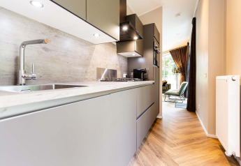 Cocina moderna de lodge con gabinetes grises, suelo de madera y vista al luminoso salón principal.