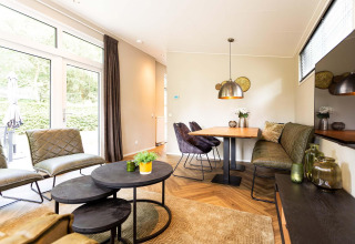 Heldere, moderne lodge woonkamer met grote ramen, knusse zithoek en eetgedeelte in de hoek.