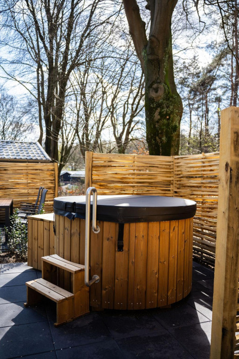 Holz-Whirlpool mit Stufen und Sichtschutz im Freien bei Heuvelrug Cottage, De Thijmse Berg, Niederlande.