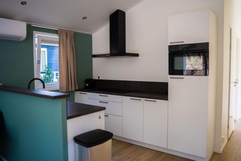 Cocina moderna en Heuvelrug Cottage con armarios blancos, encimera oscura y horno, De Thijmse Berg, Países Bajos.
