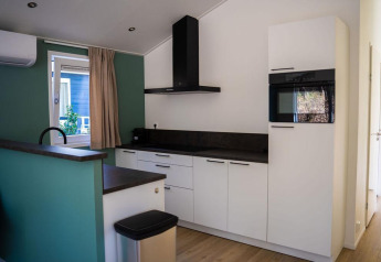 Moderne køkken i Heuvelrug Cottage med hvide skabe, sort bordplade og ovn, De Thijmse Berg, Holland.