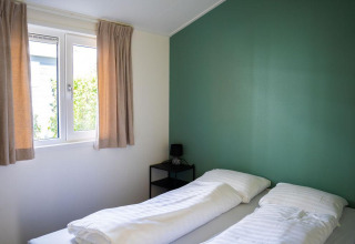Lichte slaapkamer in Heuvelrug Cottage bij De Thijmse Berg in Nederland, met groene muur en twee bedden.
