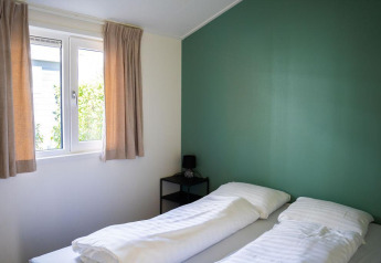 Helles Schlafzimmer im Heuvelrug Cottage bei De Thijmse Berg in den Niederlanden mit zwei Betten und grüner Wand.