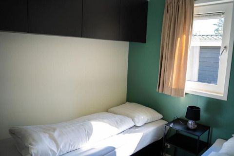 Helles Schlafzimmer mit Einzelbett, Fenster und Nachttisch in der Heuvelrug Cottage, De Thijmse Berg.