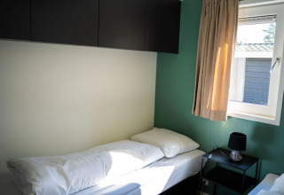 Heldere slaapkamer met eenpersoonsbed, raam en nachtkastje in Heuvelrug Cottage op De Thijmse Berg.