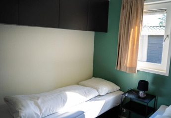 Bright bedroom with single bed, window, nightstand and cabinets at Heuvelrug Cottage, De Thijmse Berg.