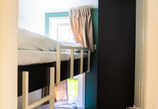 Narrow room with bunk bed, wardrobe, and window in Heuvelrug Cottage + hot tub at De Thijmse Berg, Netherlands.