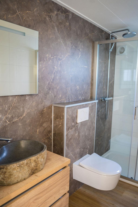 Moderne badeværelse på Heuvelrug Cottage, De Thijmse Berg, med stenvask, spejl og væghængt toilet.