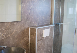 Moderne badeværelse på Heuvelrug Cottage, De Thijmse Berg, med stenvask, spejl og væghængt toilet.