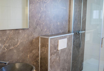 Moderne badeværelse på Heuvelrug Cottage, De Thijmse Berg, med stenvask, spejl og væghængt toilet.