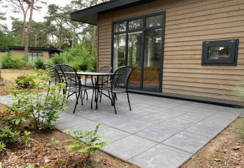 Udendørs terrasse ved et lille træhus i skovområde på Holiday park De Kleine Belties i Holland.