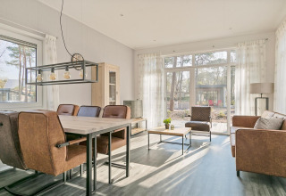 Helles Wohnzimmer mit modernen Möbeln und großen Fenstern im Forest park chalet, De Kleine Belties, Niederlande.