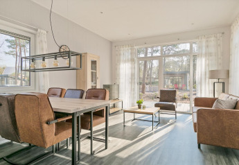 Lichte woonkamer met moderne meubels en grote ramen in Forest park chalet, De Kleine Belties, Nederland.