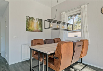 Eethoek in Forest park chalet met bruine stoelen, moderne verlichting en zicht op natuur in De Kleine Belties.