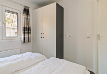 Lyst soveværelse i Forest park chalet ved Holiday park De Kleine Belties, med skab og vindue.