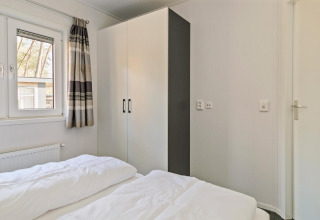 Bright bedroom in Forest park chalet at Holiday park De Kleine Belties, featuring wardrobe and window.