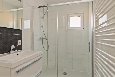 Modernes kleines Badezimmer mit Dusche, Waschbecken, Spiegel und Fenster im Forest park chalet, Niederlande.