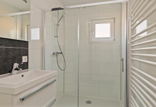 Baño pequeño y moderno con ducha, lavabo, espejo y ventana en Forest park chalet, De Kleine Belties, Países Bajos.