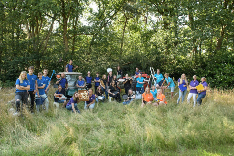 Equipo numeroso posando en un alojamiento glamping, rodeados de utensilios y naturaleza al aire libre.