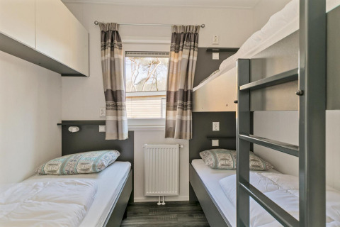 Dormitorio luminoso con literas y camas individuales en Forest park chalet, Holiday park De Kleine Belties, Países Bajos.