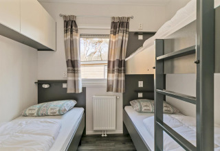 Dormitorio luminoso con literas y camas individuales en Forest park chalet, Holiday park De Kleine Belties, Países Bajos.