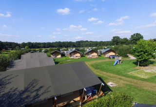 Tiendas safari en el parque vacacional De Boshoek, Países Bajos, con césped verde y juegos infantiles al aire libre.