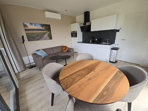 Sala moderna de lodge en los Países Bajos con mesa redonda, cocina, sofá y obra de arte en la pared.