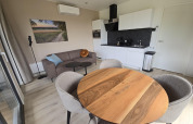 Sala moderna de lodge en los Países Bajos con mesa redonda, cocina, sofá y obra de arte en la pared.