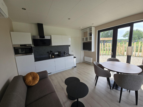 Sala y cocina modernas en la Water lodge 2 Deluxe, Hofparken Wiltershaar, Países Bajos, con vista al jardín.