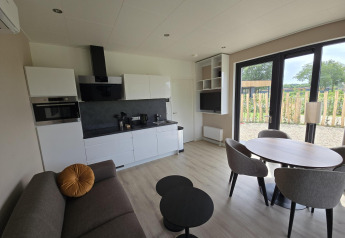 Sala y cocina modernas en la Water lodge 2 Deluxe, Hofparken Wiltershaar, Países Bajos, con vista al jardín.