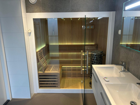 Sauna moderna con puerta de cristal y bancos de madera en el Water Lodge 2 Deluxe de Hofparken Wiltershaar.