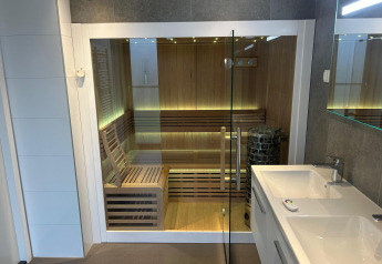 Sauna moderna con puerta de cristal y bancos de madera en el Water Lodge 2 Deluxe de Hofparken Wiltershaar.