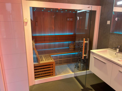 Sauna moderna con puerta de cristal y bancos de madera en Water lodge 2 Deluxe de Hofparken Wiltershaar.