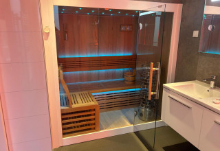 Sauna moderna con puerta de cristal y bancos de madera en Water lodge 2 Deluxe de Hofparken Wiltershaar.
