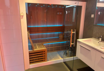 Sauna moderna con puerta de cristal y bancos de madera en Water lodge 2 Deluxe de Hofparken Wiltershaar.