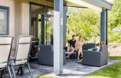 Familie genießt die Terrasse der Forest Lodge DeLuxe im Kampeerdorp de Zandstuve in den Niederlanden.