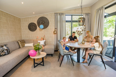 Familie genießt die Zeit im modernen Forest Lodge DeLuxe im Kampeerdorp de Zandstuve, Niederlande.