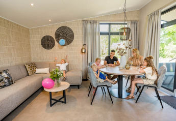 Familie genießt die Zeit im modernen Forest Lodge DeLuxe im Kampeerdorp de Zandstuve, Niederlande.