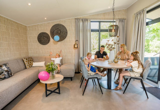 Familie hygger sig i den moderne Forest Lodge DeLuxe på Kampeerdorp de Zandstuve, Nederlandene.