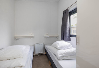 Schlafzimmer mit zwei Einzelbetten, weißer Bettwäsche und großem Fenster in der Forest Lodge DeLuxe.