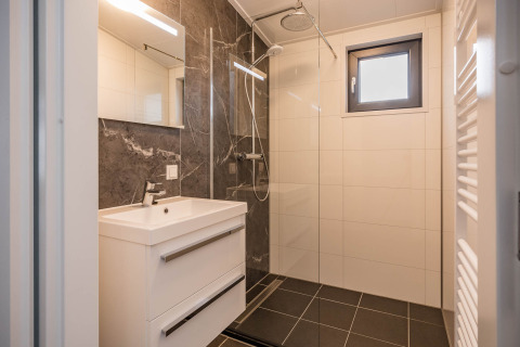 Modernes Badezimmer der Forest Lodge DeLuxe im Kampeerdorp de Zandstuve mit Regendusche und elegantem Design.