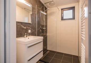 Modernes Badezimmer der Forest Lodge DeLuxe im Kampeerdorp de Zandstuve mit Regendusche und elegantem Design.