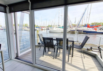 Husboat Havenlodge N på Marina Parcs Naarden i Holland med udsigt over marinaens lystbåde fra terrassen.