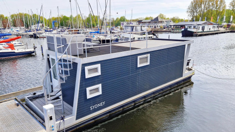 Modern houseboat named Havenlodge N at Marina Parcs Naarden in the Netherlands, docked in a marina.